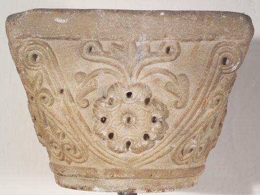 Capitel de piedra con flor de ocho pétalos y otros motivos fitomorfos