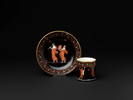 Cup and saucer with a Bacchic scene with red figures on a black background
