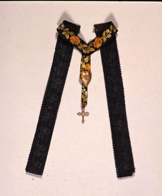 Cruz dorada decorada atada con cinta bordada y corazón grabado